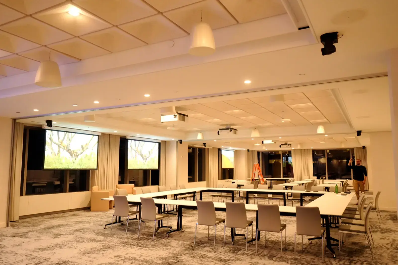 Large meeting room with dual projection screens and ceiling cameras