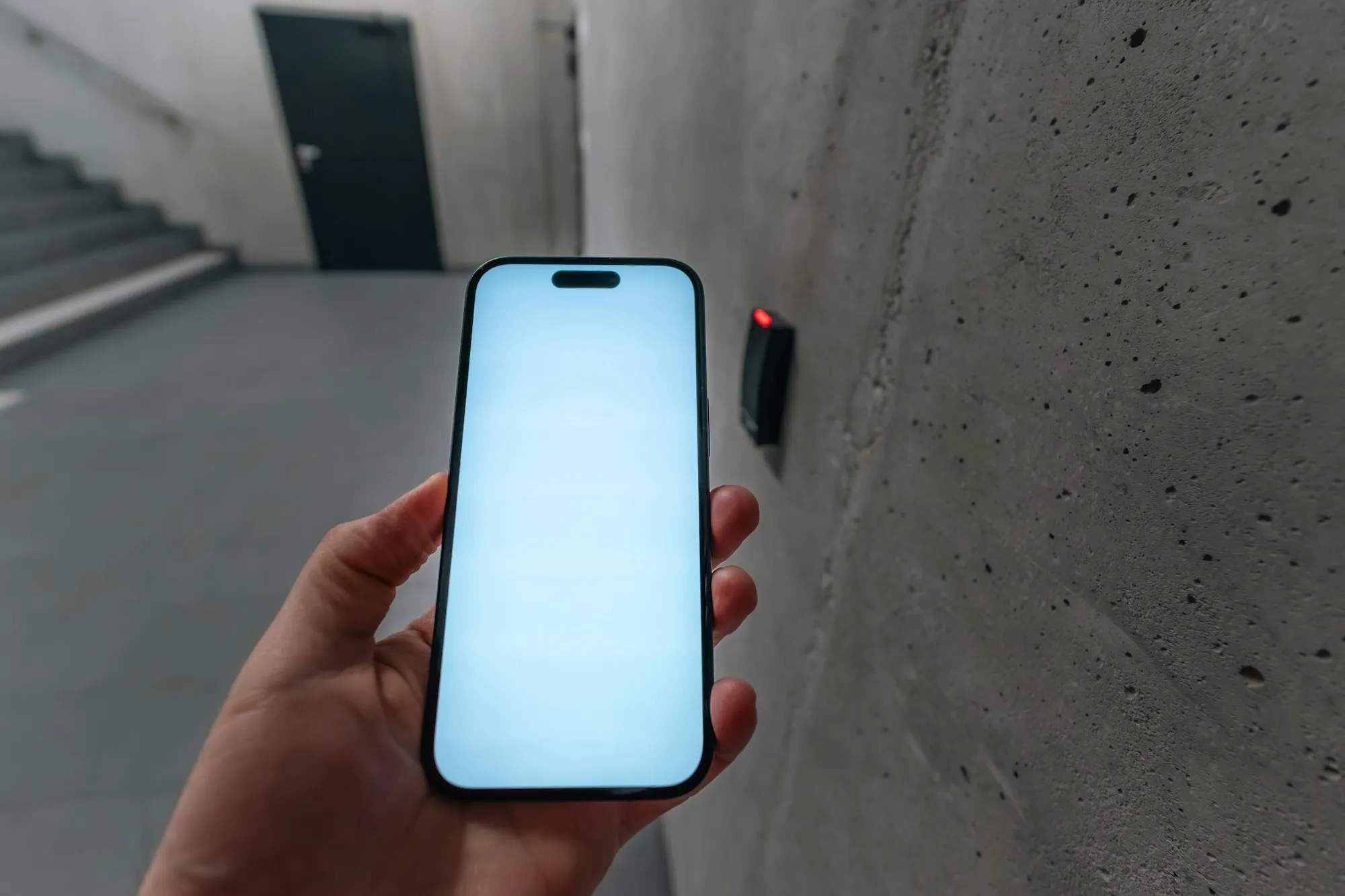 Phone held up to a wall-mounted door reader as a mobile credential