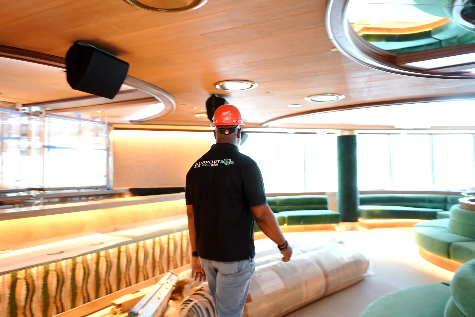 DIST technician walking a venue during construction with speakers installed overhead