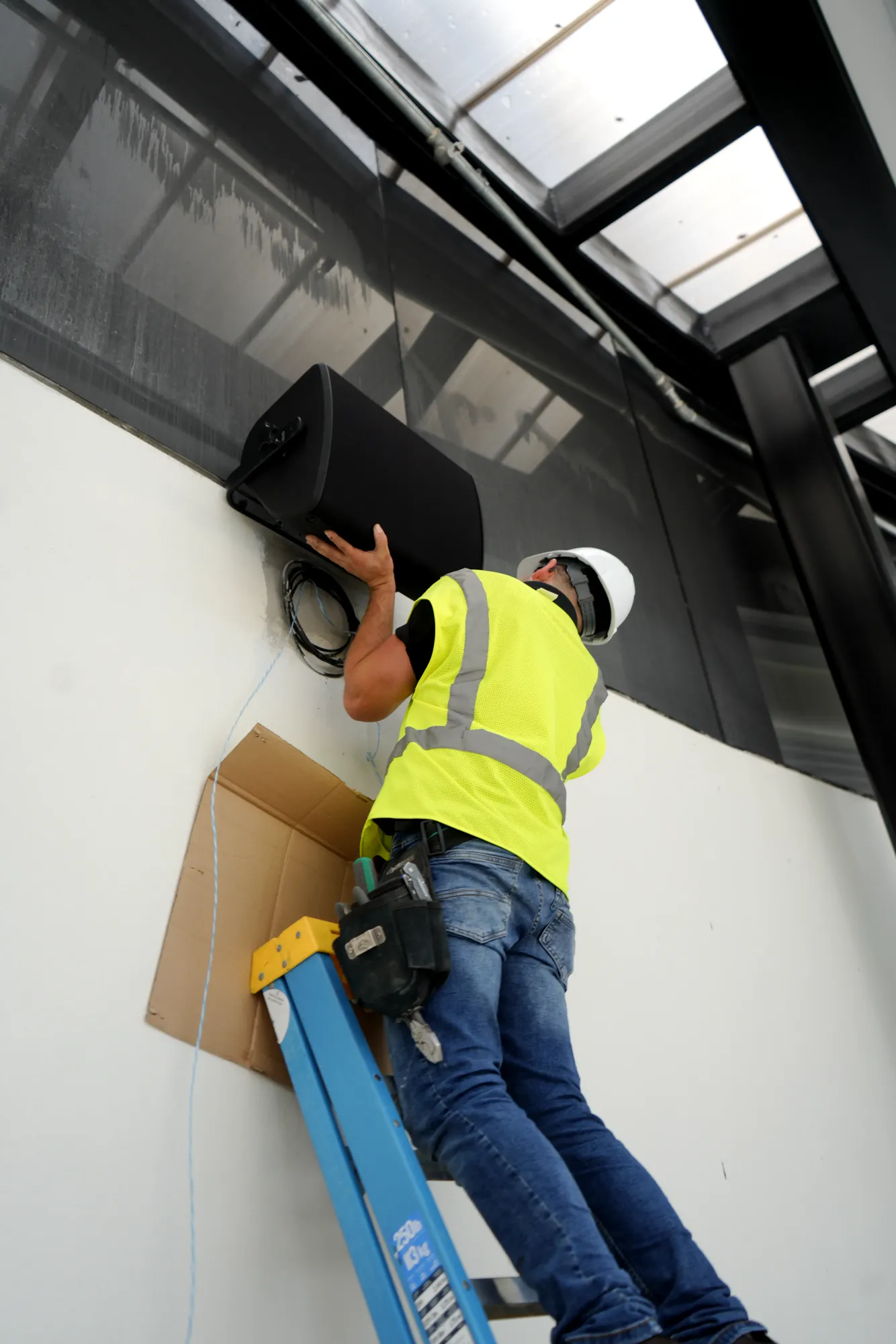 DIST installer mounting a loudspeaker on a wall